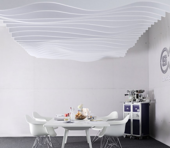 Der moderne, minimalistische Raum der Untergruppe designed acoustic aus dem Jahr 2009 zeigt eine weiße Tischgruppe unter einer wellenförmigen, akustisch wirksamen Deckenkonstruktion mit einer Kaffee-Servierstation rechts.