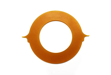 Das Bild zeigt eine flache, ringförmige Dichtung aus einem bernsteinfarbenen elastischen Material, die an zwei gegenüberliegenden Seiten spitze, Ausbuchtungen aufweist.