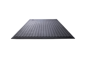 Eine schwarze Gummimatte mit einer rutschfesten Noppenstruktur ist aus einer flachen Perspektive fotografiert.