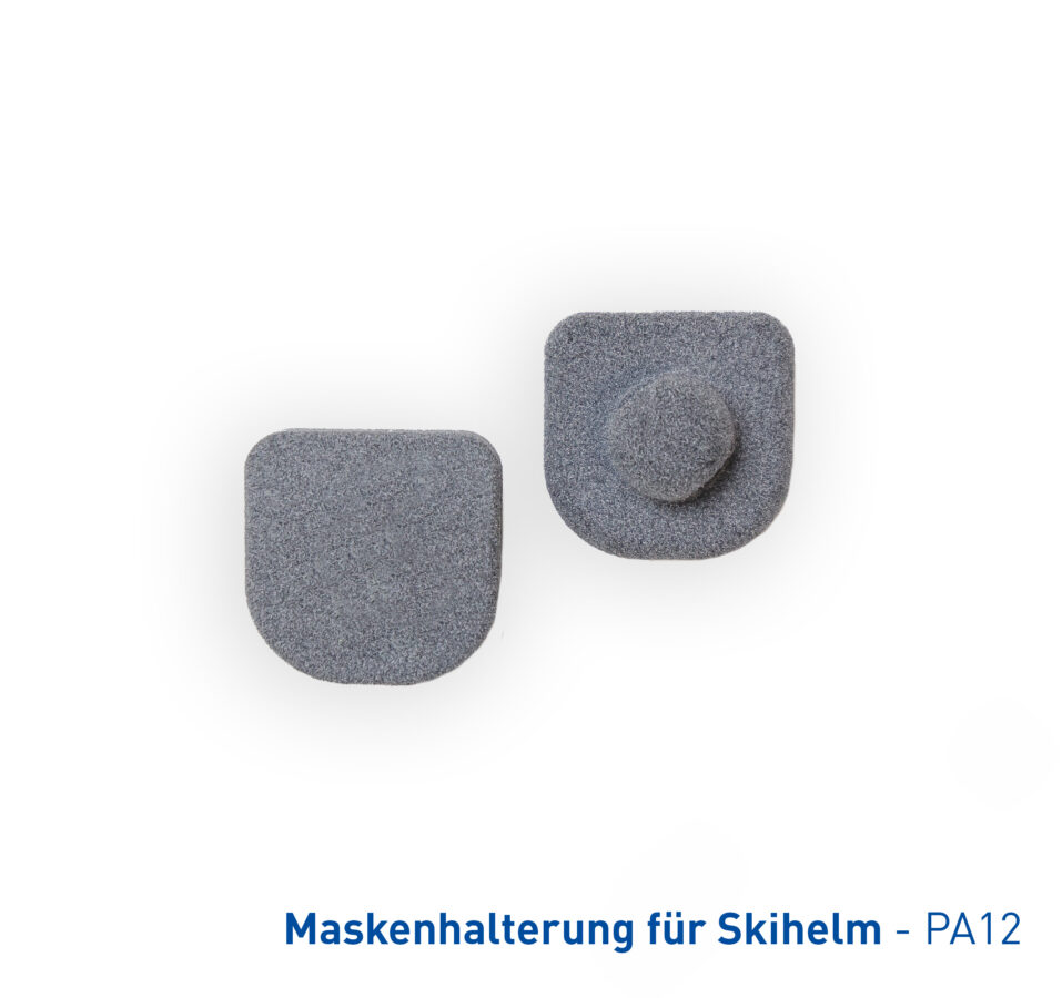 Das Bild zeigt zwei graue Bauteile einer Maskenhalterung für Skihelme, die ebenfalls aus dem robusten Kunststoff PA12 gefertigt wurden.