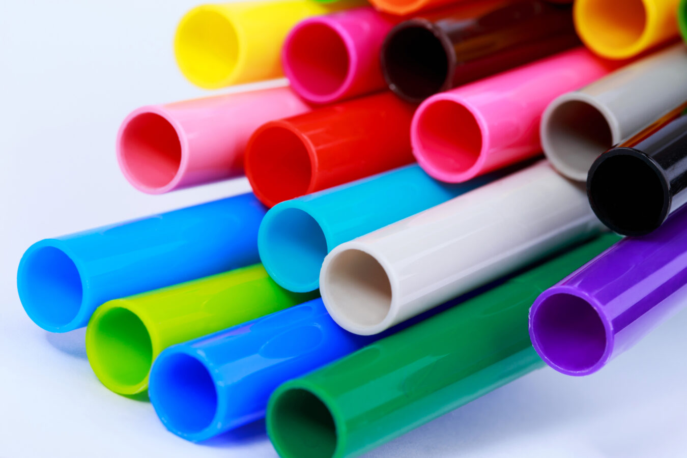 Zu sehen ist ein Bündel farbenfroher Kunststoffrohre in leuchtenden Gelb-, Rot-, Blau- und Violetttönen.