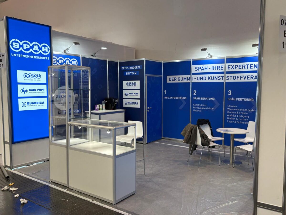 Der Späh-Stand auf der Messe zeigt eine Vitrine, Informationswände sowie einen Tisch mit Stühlen.