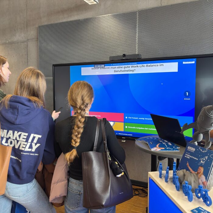 Ausbildungsmessestand der Karrierebörse an der FH Albstadt-Sigmaringen. Es wird an einem großen Bildschirm ein Kommunikationsspiel gespielt