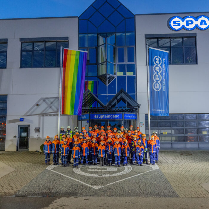 Gruppenfoto von vielen Kindern aus der Jugendfeuerwehr vor dem Haupteingang von Späh. Alle Kinder sind einheitlich in ihrer Jugendfeuerwehrkleidung.