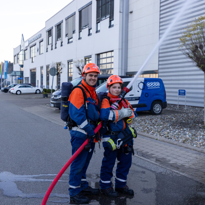 Zwei Jungen aus der Jugendfeuerwehr stehen vor dem Späh Gebäude und geben mit dem Schlauch ein Strahl in die Luft ab.