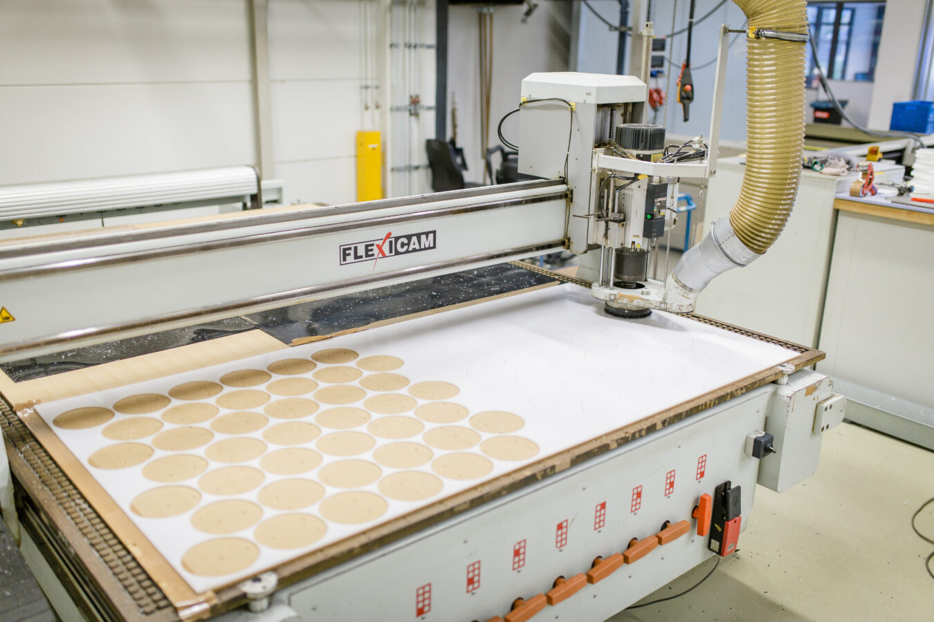 Fräsplotter die runde Teile herstellt aus weißem Plattenmaterial. Die Hälfte des Plattenmaterials wurde schon benutzt.