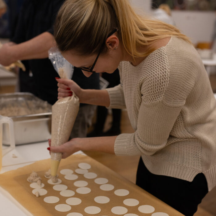 Eine Späh-Mitarbeiterin steht vor einem Backblech und gibt Spritzgebäck auf das Blech.